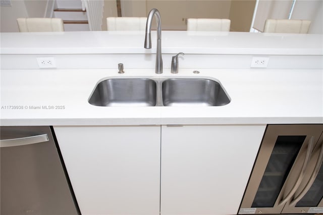 interior details with wine cooler, sink, and white cabinets