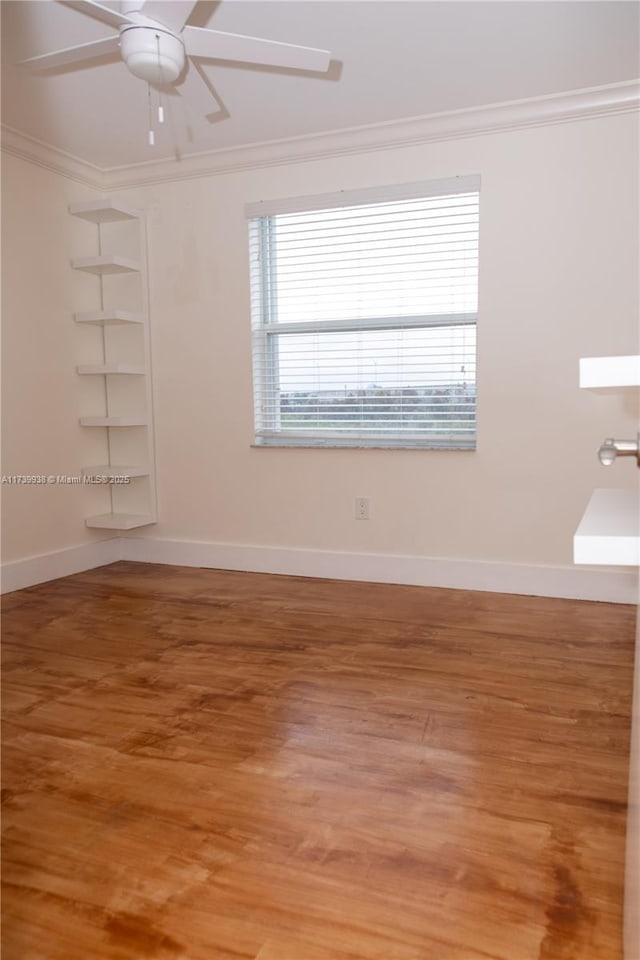 empty room featuring hardwood / wood-style floors, crown molding, built in shelves, and ceiling fan