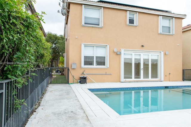 rear view of property featuring a fenced in pool, a patio area, and french doors