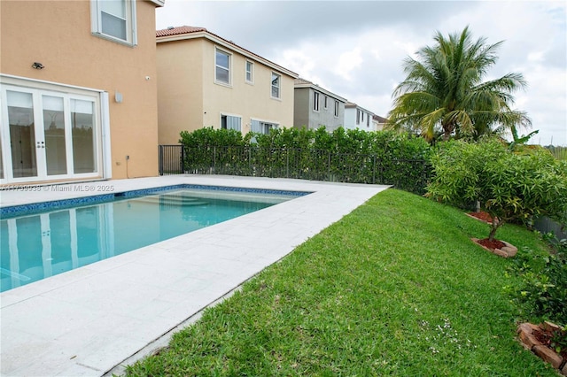 view of swimming pool with a lawn and french doors