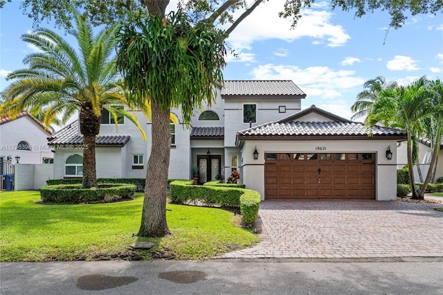 mediterranean / spanish house featuring a garage and a front lawn