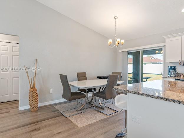 dining space featuring lofted ceiling, light hardwood / wood-style floors, and a chandelier