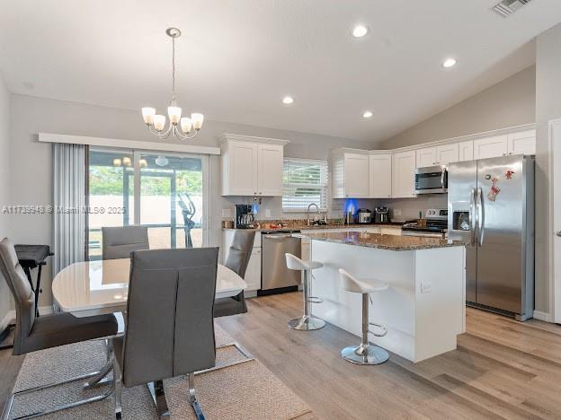 kitchen featuring sink, decorative light fixtures, a kitchen island, stainless steel appliances, and white cabinets