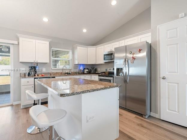 kitchen with white cabinetry, a kitchen breakfast bar, a center island, and appliances with stainless steel finishes