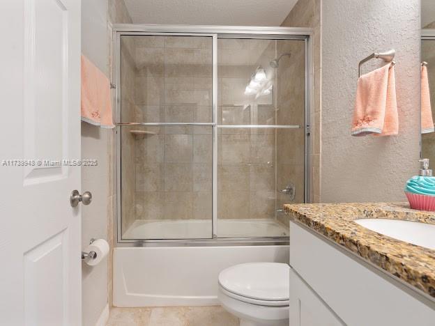 full bathroom featuring enclosed tub / shower combo, vanity, tile patterned floors, and toilet