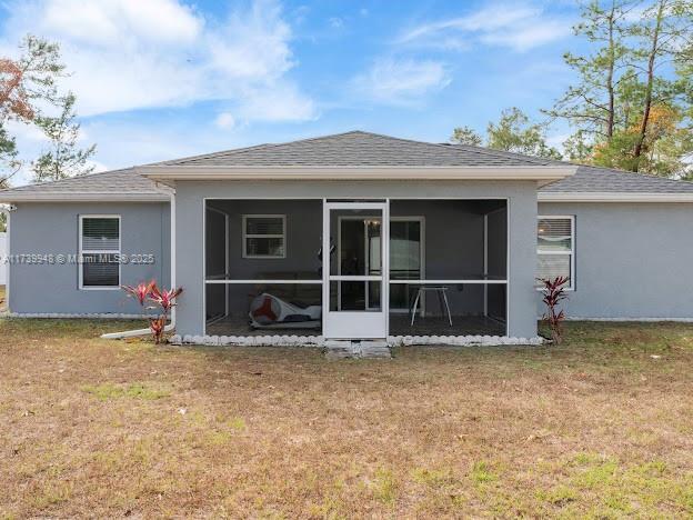 back of property with a yard and a sunroom