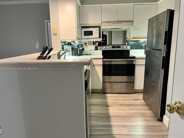 kitchen with light hardwood / wood-style flooring, ornamental molding, kitchen peninsula, stainless steel appliances, and white cabinets