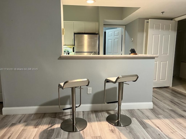 kitchen with light hardwood / wood-style floors, stainless steel refrigerator, and white cabinets