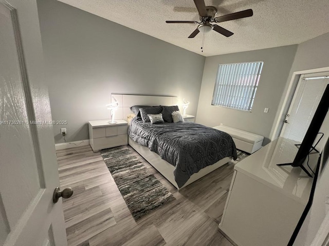 bedroom with ceiling fan, light hardwood / wood-style floors, and a textured ceiling