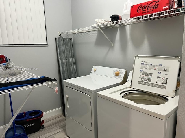 clothes washing area with washing machine and dryer and light wood-type flooring