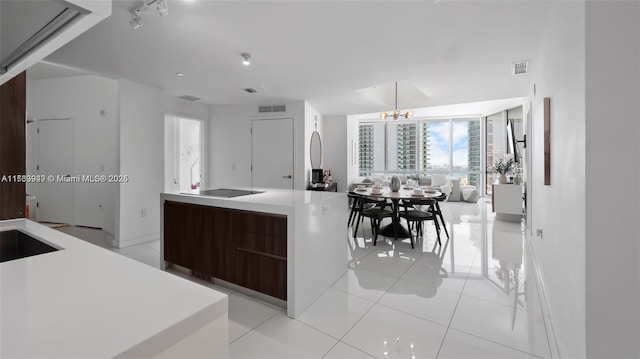 851 NE 1st Ave Unit 3303, Miami, FL 33132 - kitchen featuring dark brown cabinetry, a center island, light tile patterned floors, black electric cooktop, and a notable chandelier