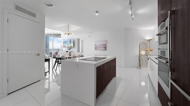 851 NE 1st Ave Unit 3303, Miami, FL 33132 - kitchen with a kitchen island, stainless steel oven, black electric cooktop, and light tile patterned floors