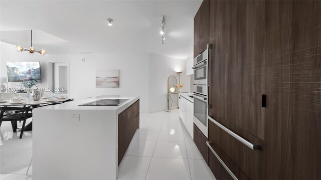 851 NE 1st Ave Unit 3303, Miami, FL 33132 - kitchen featuring light tile patterned floors, an inviting chandelier, hanging light fixtures, a center island, and black electric stovetop