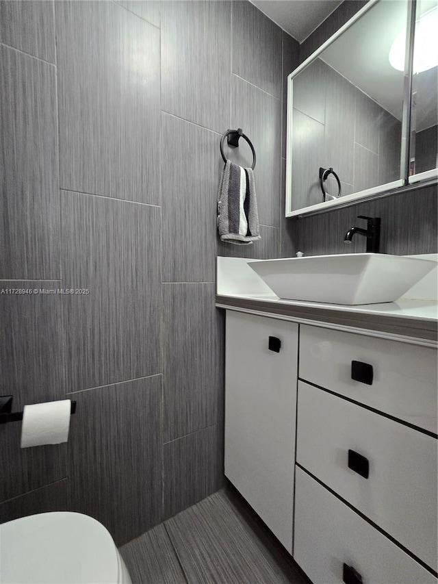 bathroom featuring vanity, tile walls, and toilet