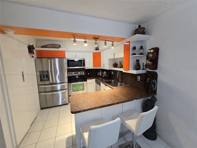 kitchen with sink, white cabinetry, a textured ceiling, kitchen peninsula, and stainless steel appliances