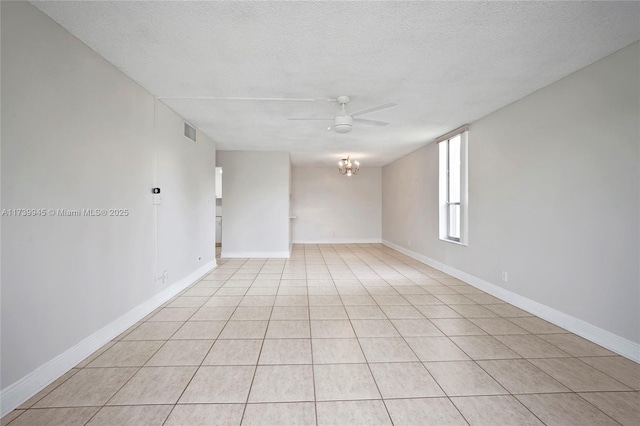 tiled spare room featuring ceiling fan with notable chandelier and a textured ceiling