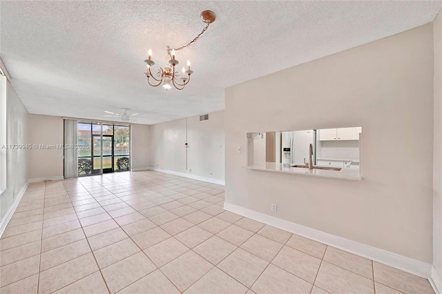 empty room featuring sink, light tile patterned floors, a textured ceiling, and a chandelier