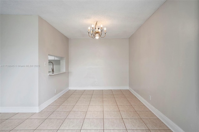 empty room with an inviting chandelier, sink, a textured ceiling, and light tile patterned floors