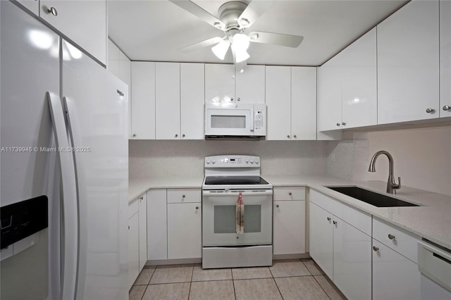 kitchen with sink, white appliances, light tile patterned floors, ceiling fan, and white cabinetry