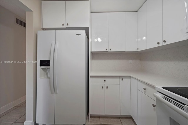 kitchen featuring white cabinetry, light tile patterned flooring, and white appliances