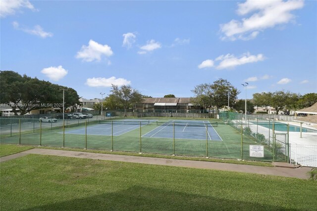 view of tennis court featuring a lawn