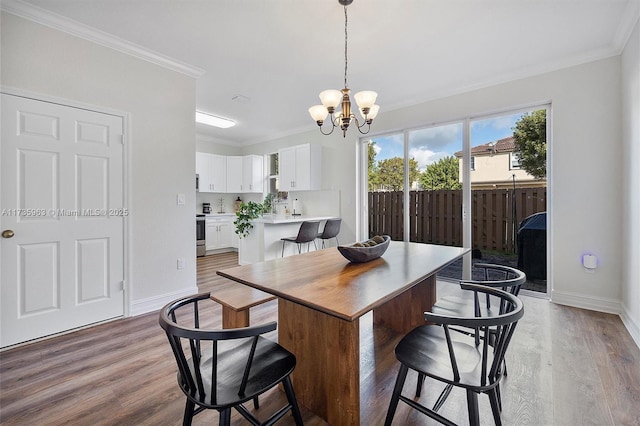 dining room with a notable chandelier, ornamental molding, and light wood-type flooring