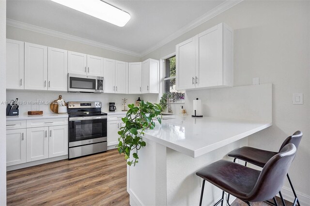 kitchen featuring appliances with stainless steel finishes, a breakfast bar, and white cabinets