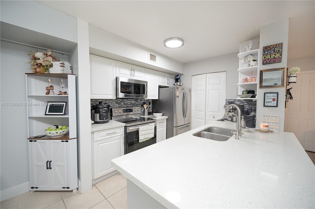 kitchen featuring light tile patterned flooring, sink, white cabinetry, appliances with stainless steel finishes, and decorative backsplash