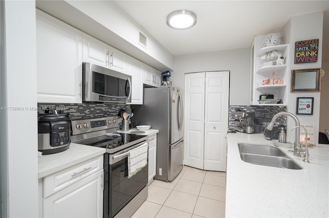 kitchen featuring light tile patterned flooring, tasteful backsplash, white cabinetry, sink, and stainless steel appliances