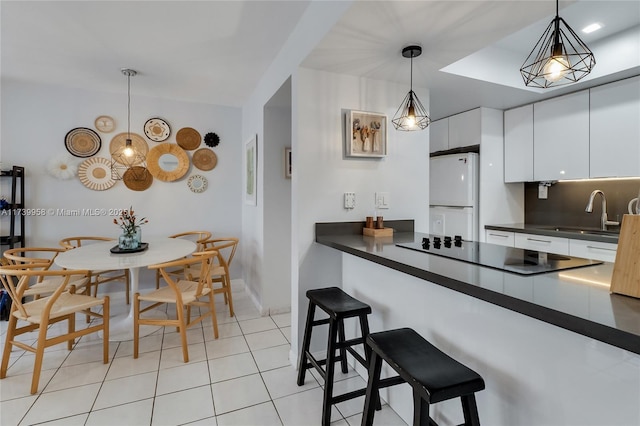 kitchen with sink, white cabinetry, hanging light fixtures, white refrigerator, and a kitchen breakfast bar