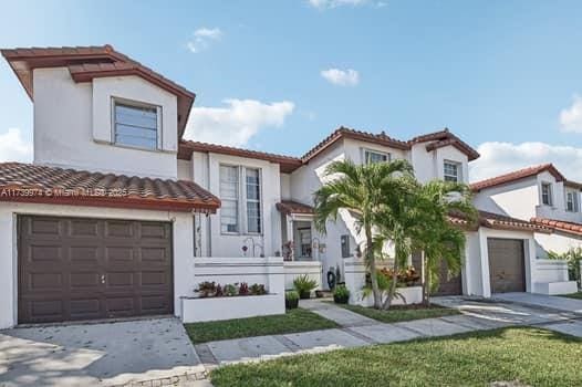 mediterranean / spanish house with a tile roof, driveway, an attached garage, and stucco siding