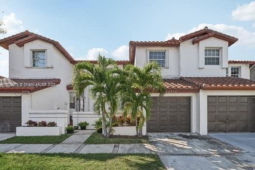 mediterranean / spanish-style home featuring concrete driveway, an attached garage, a tiled roof, and stucco siding