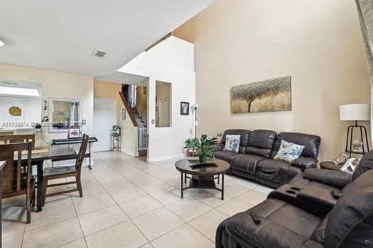 living area featuring visible vents, stairway, and light tile patterned floors