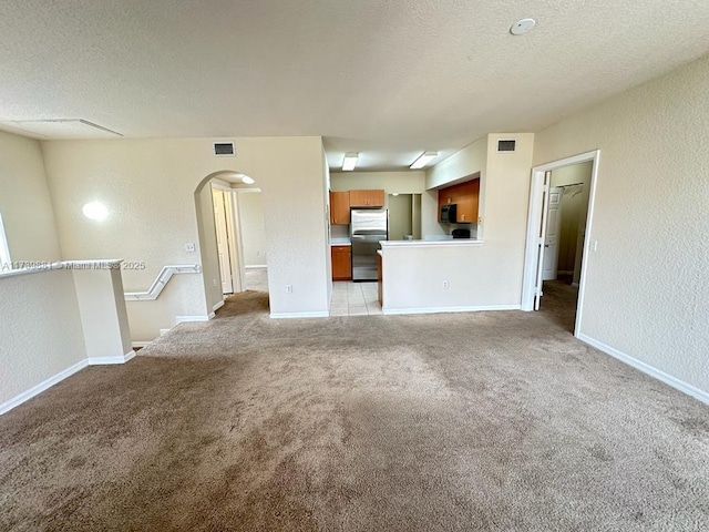 unfurnished living room with light colored carpet and a textured ceiling