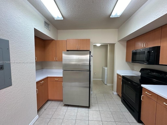 kitchen featuring light tile patterned floors, electric panel, black appliances, a textured ceiling, and washer / dryer