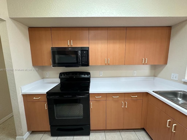 kitchen with sink, light tile patterned floors, and black appliances