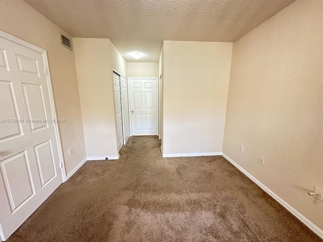 empty room featuring a textured ceiling and dark colored carpet