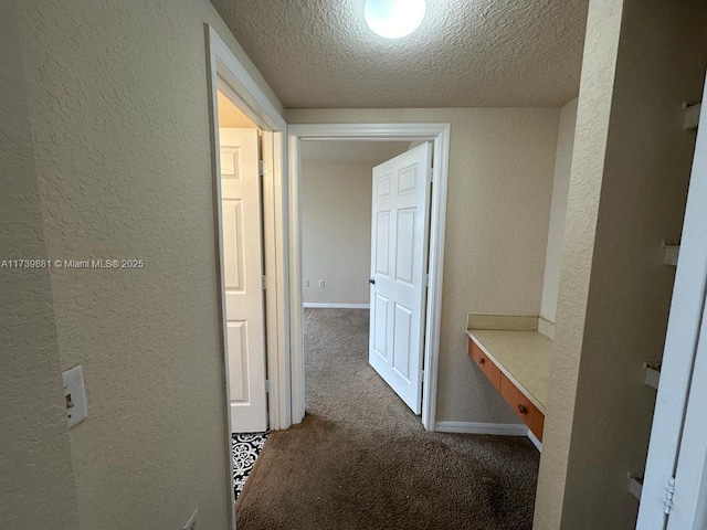 hallway featuring carpet flooring and a textured ceiling