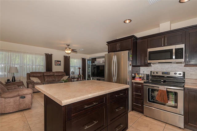 kitchen featuring dark brown cabinetry, stainless steel appliances, a center island, and backsplash