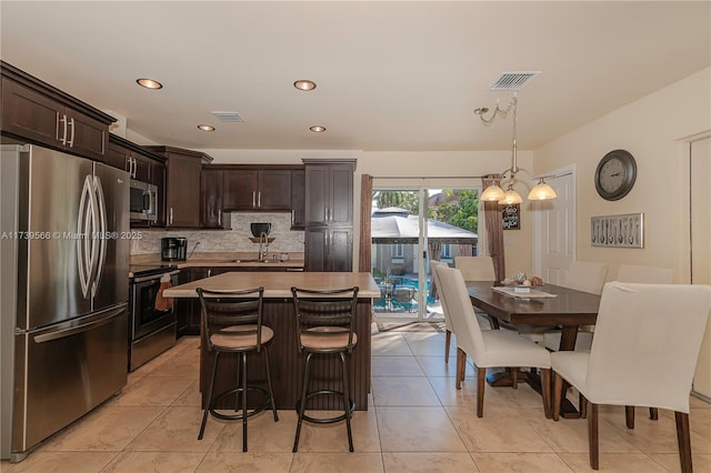 kitchen with stainless steel appliances, a center island, dark brown cabinetry, and decorative light fixtures