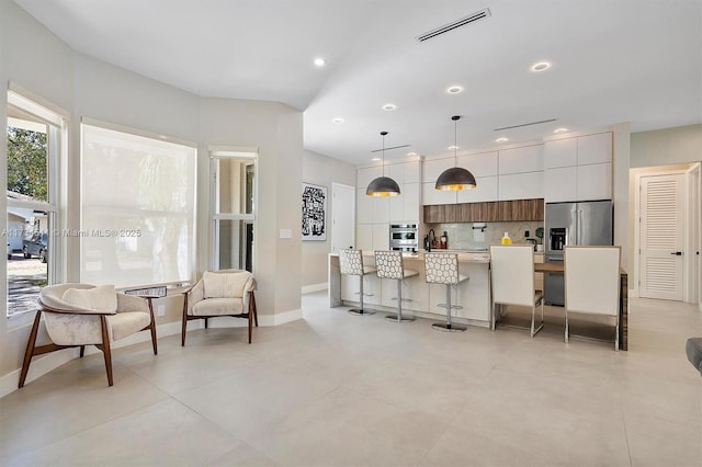 kitchen with tasteful backsplash, a kitchen breakfast bar, hanging light fixtures, a kitchen island with sink, and stainless steel appliances