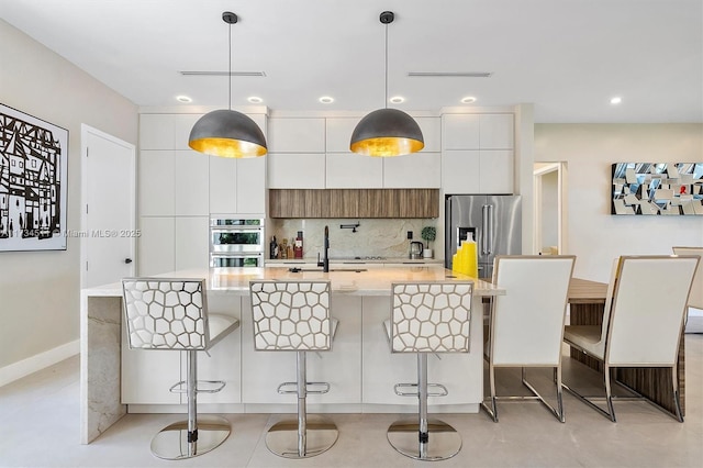 kitchen featuring hanging light fixtures, a breakfast bar, white cabinets, and appliances with stainless steel finishes