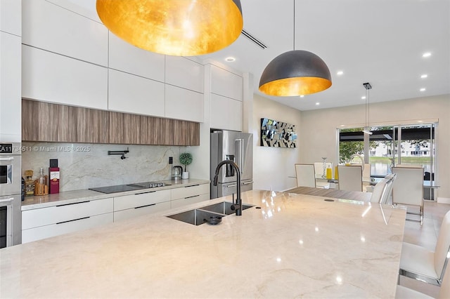 kitchen featuring sink, decorative light fixtures, stainless steel appliances, and white cabinets