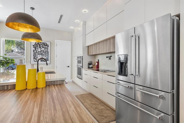 kitchen with sink, white cabinetry, tasteful backsplash, appliances with stainless steel finishes, and pendant lighting