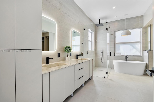 bathroom with tile walls, vanity, tile patterned floors, and shower with separate bathtub