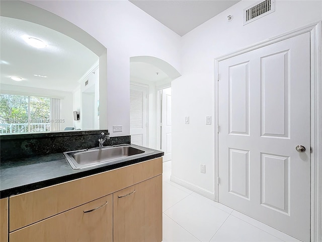 kitchen with light brown cabinetry, sink, and light tile patterned floors