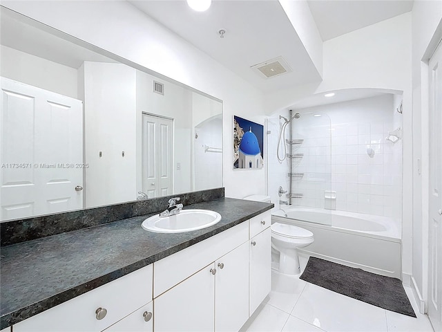 full bathroom with tile patterned flooring, tiled shower / bath, vanity, and toilet