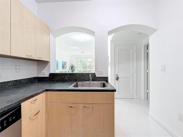 kitchen with light tile patterned flooring, light brown cabinetry, dishwasher, and sink