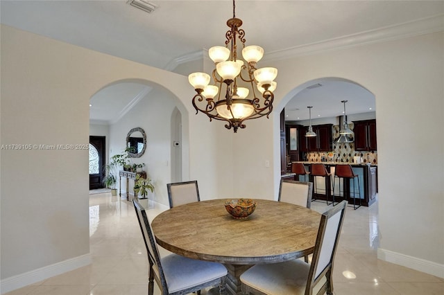 tiled dining room with an inviting chandelier and ornamental molding