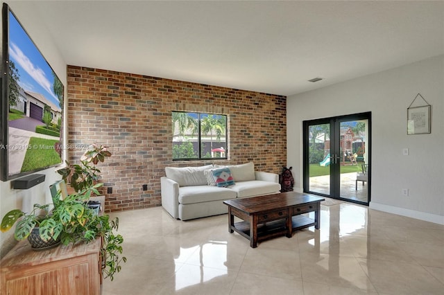 living room featuring light tile patterned flooring, brick wall, a healthy amount of sunlight, and french doors